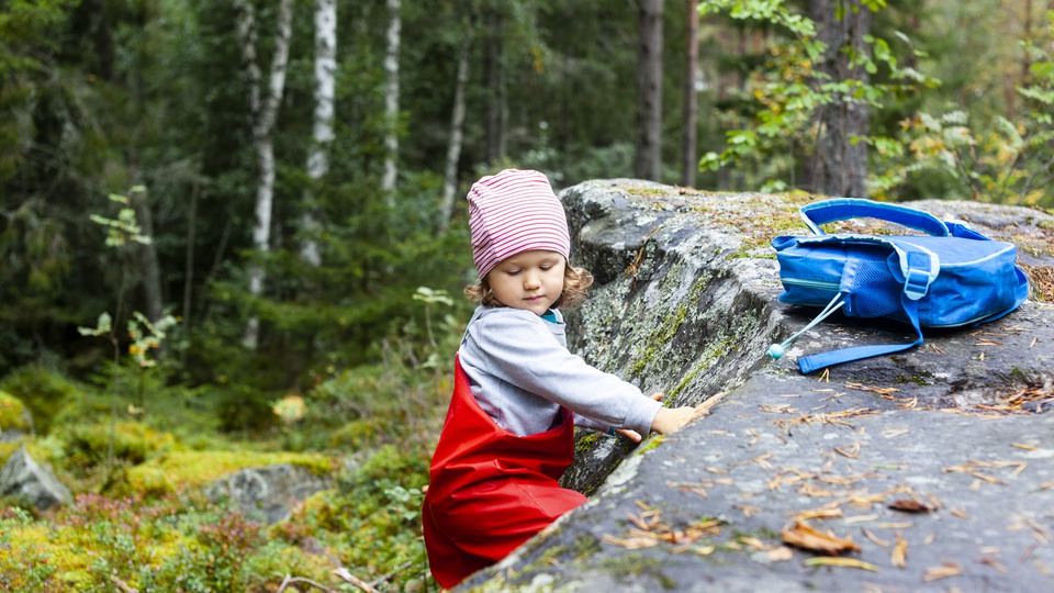 Barn leker i skogen, lutar sig mot sten