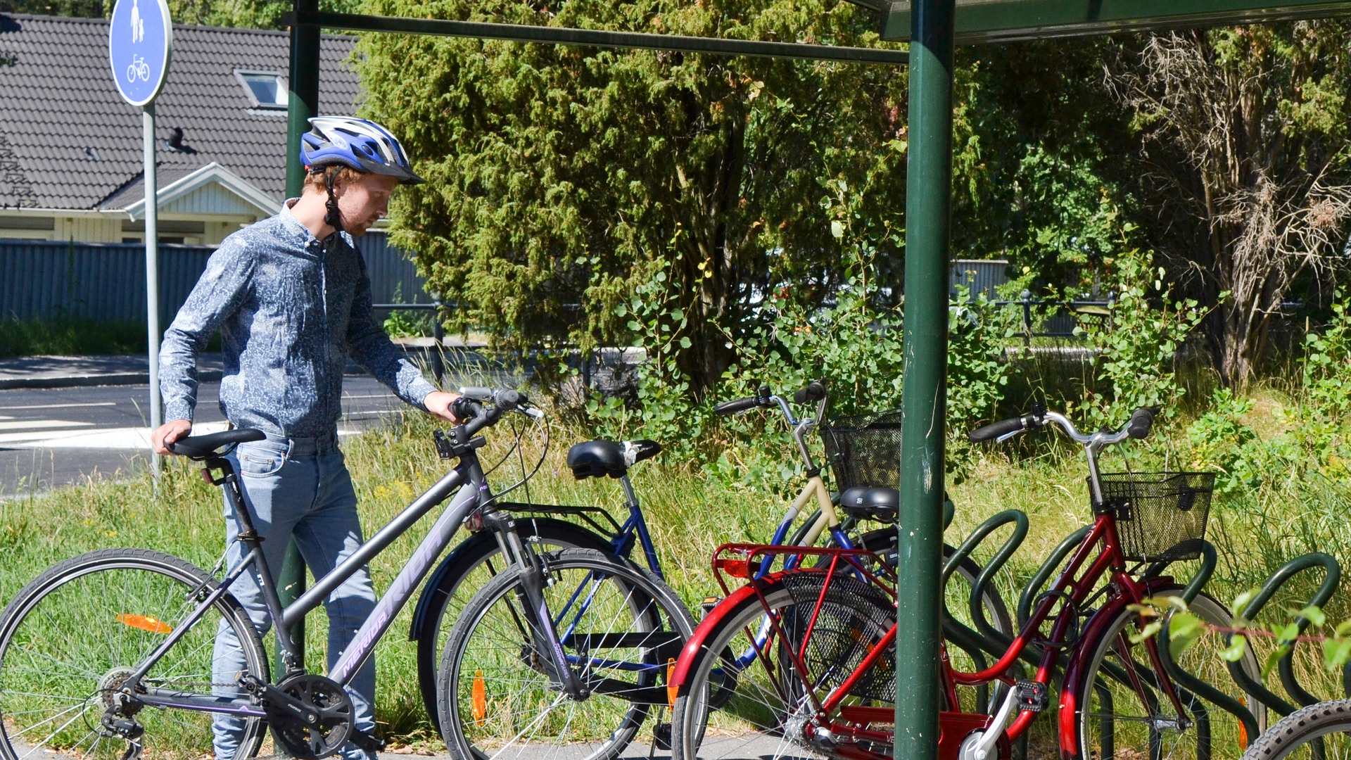 Kille parkerar cykel i cykelställ.