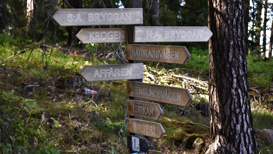 Vägvisare i trä som visar vägen till bland annat Norra bryggan på Ingmarsö.