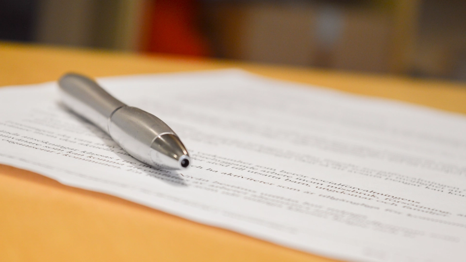En penna ligger på ett papper med text.