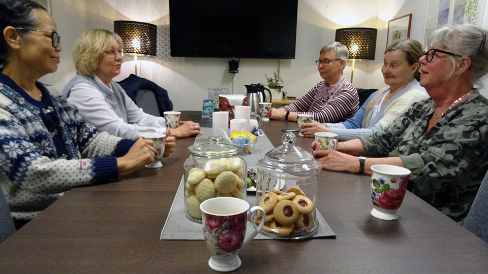 Fem kvinnor sitter runt ett fikabord. Det ser ut att vara en trevlig stämning.