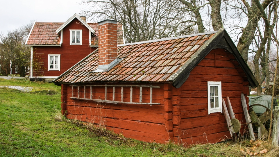 Liten röd komplementbyggnad i timmer