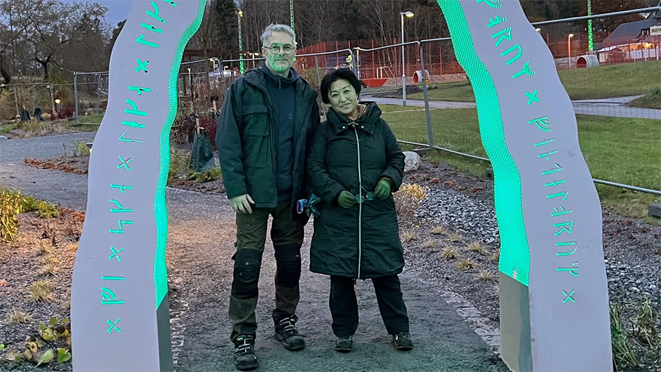 En man och en kvinna står under en båge som lyser i grönt.