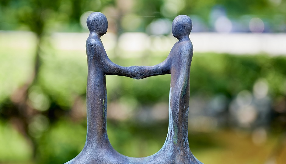 En liten staty med två figurer som handhälsar på varandra.