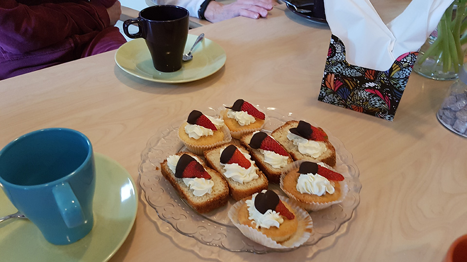 Ett fat med dekorerade kakor och kaffekoppar.