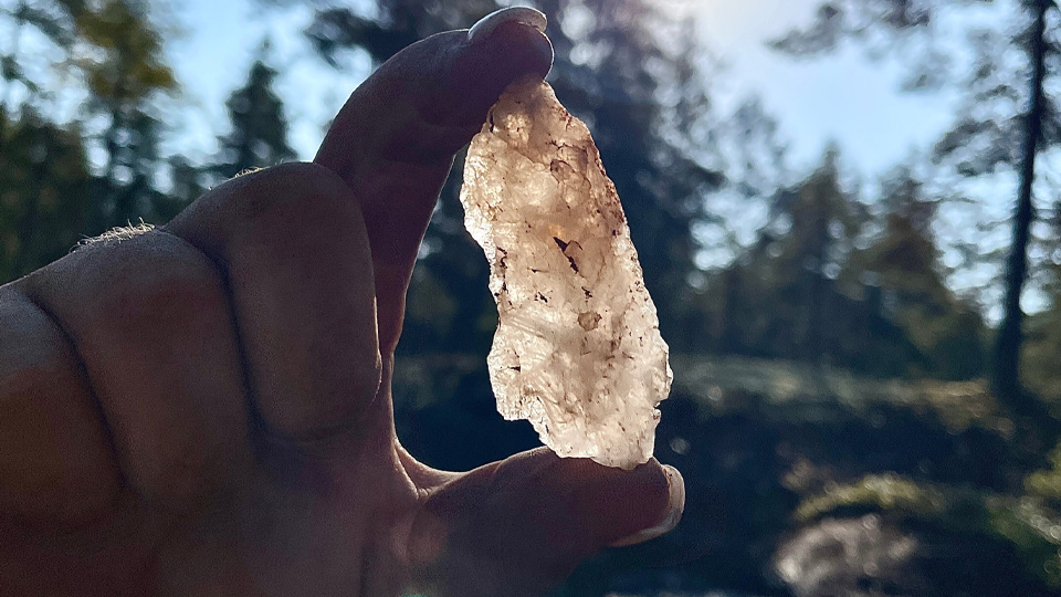 Någon håller upp en bit kvarts mellan tummen och pekfingret.