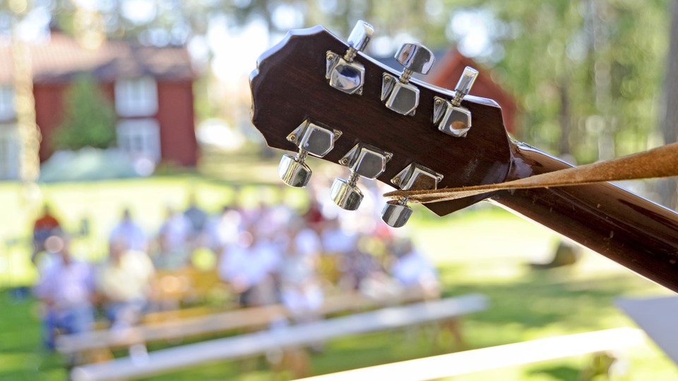 Gitarrhuvud med publik i bakgrunden.