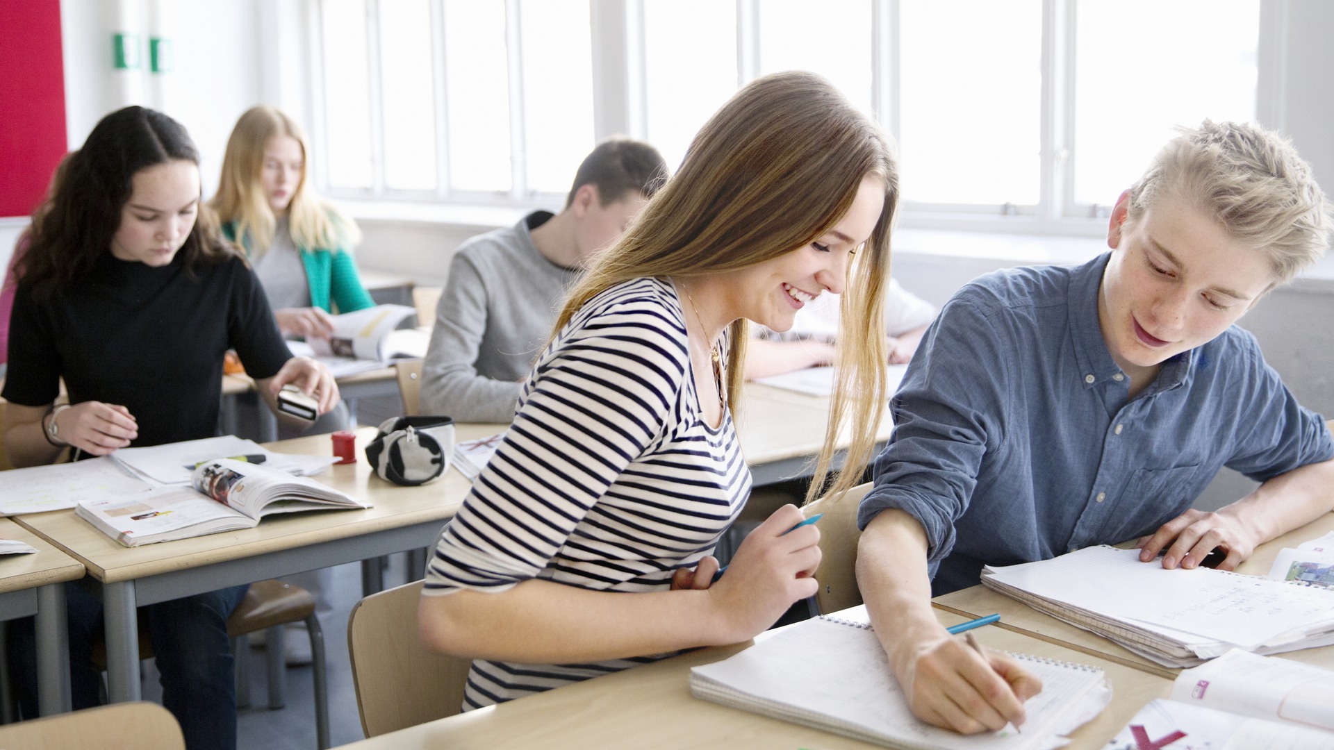 Ungdomar i klassrum arbetar i sina bänkar