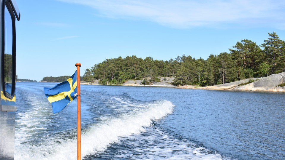 Båt åker fort med en svensk flagga som vajar i vinden