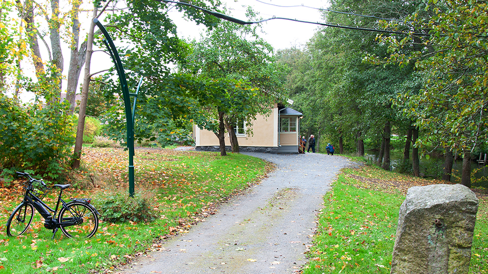 Slussvaktarbostaden, ett gult putshus i en lummig grön trädgård. En grusstig leder fram till huset.