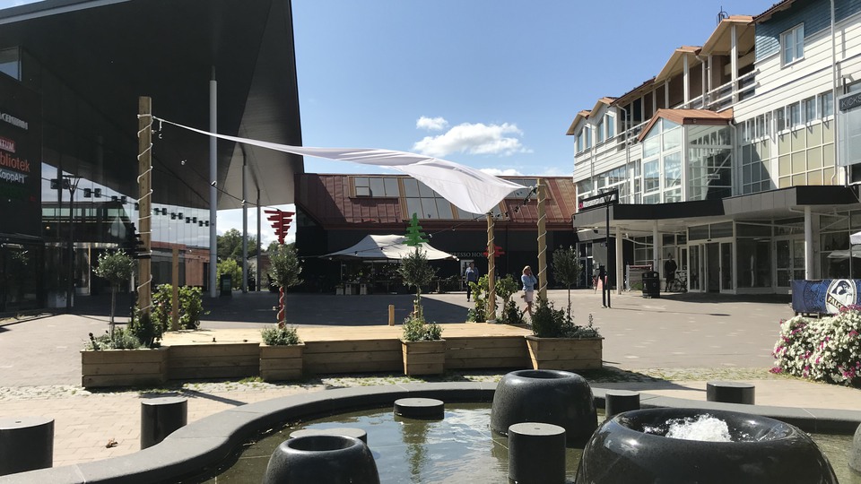 Torg centralt i Åkersberga, Österåker. Fontän, sittplats i trä med segelduk samt centrum i bakgrunden