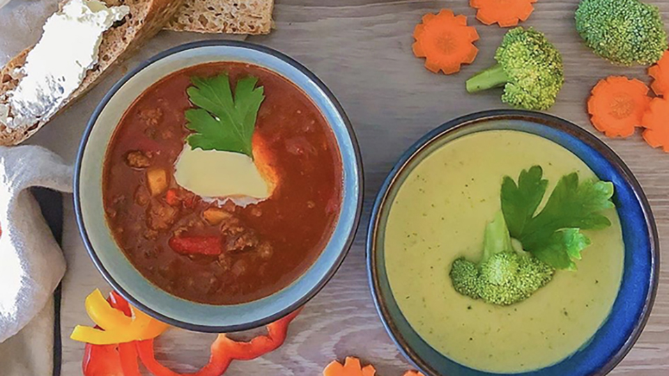 Två djuptallrikar med soppa i och grönsaker på bordet för dekoration.