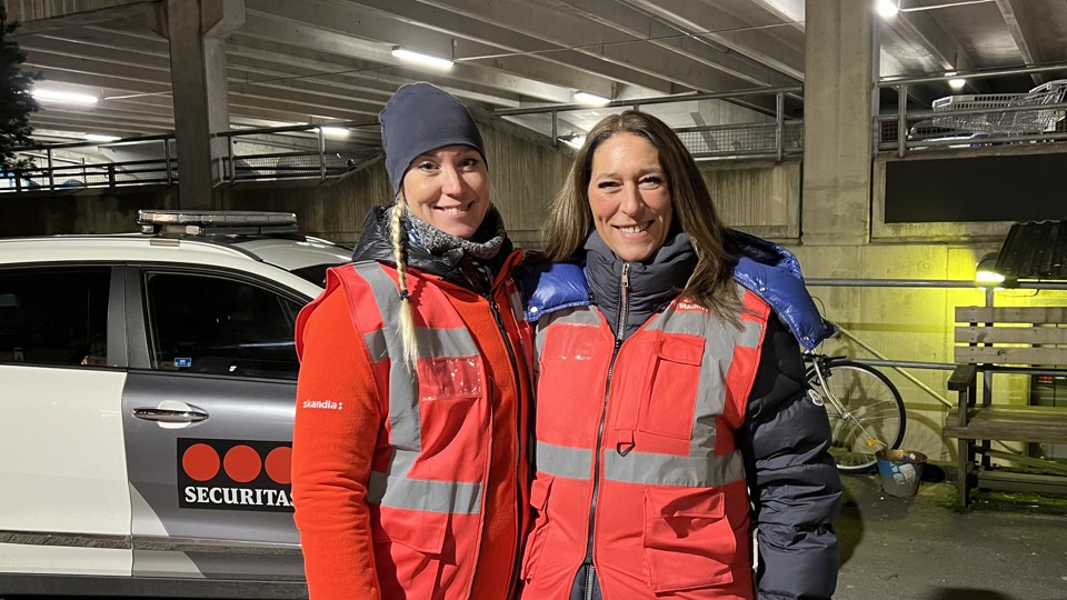 Bilden visar Michaela Fletcher och en annan kvinna som står bredvid varandra utomhus i mörkret klädda i röda ytterkläder som det står nattvandring på