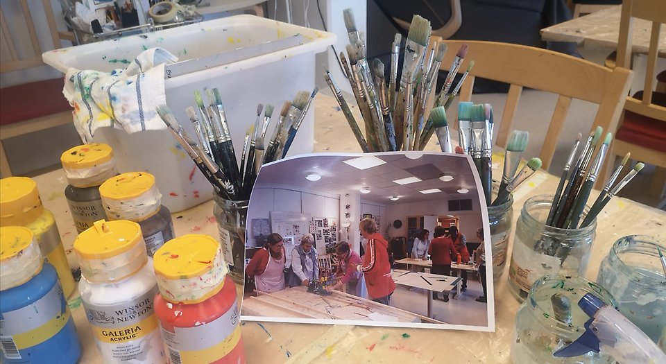 Bilden visar hur en grupp seniorer målar tillsammans i en ateljé.