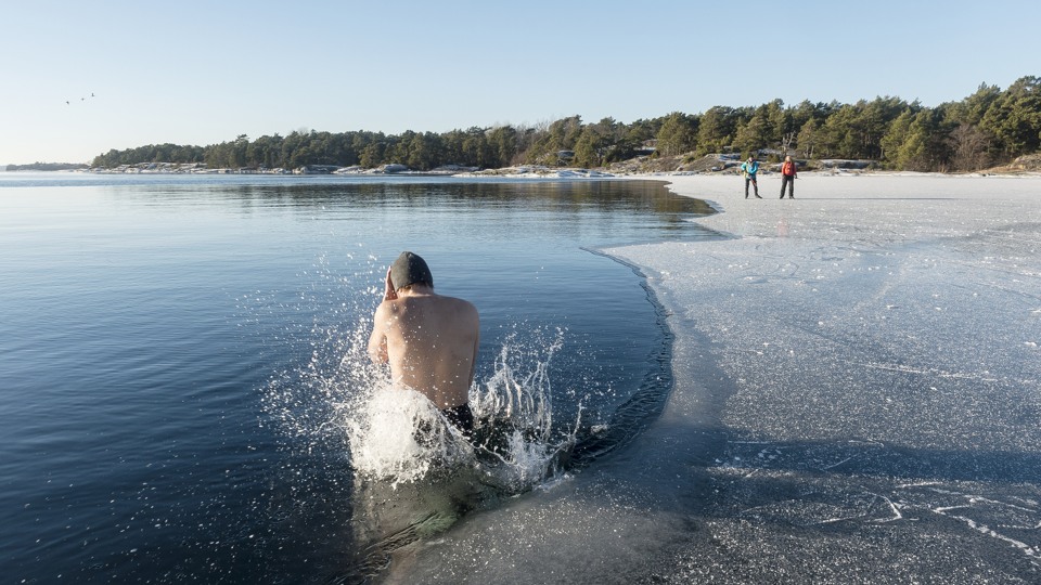 Bilden visar en person som vinterbadar och två som åker skridskor på isen.