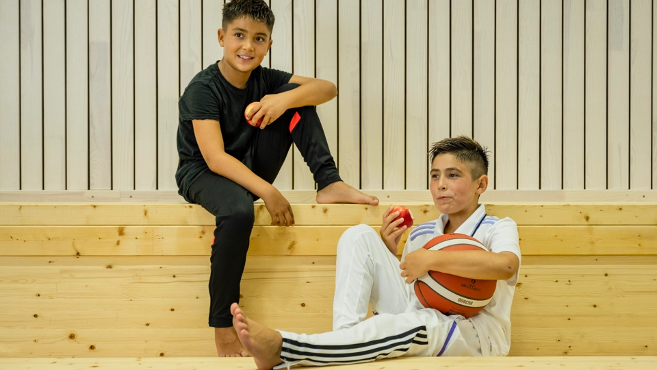 Två unga killar med basketboll i multiarenan.