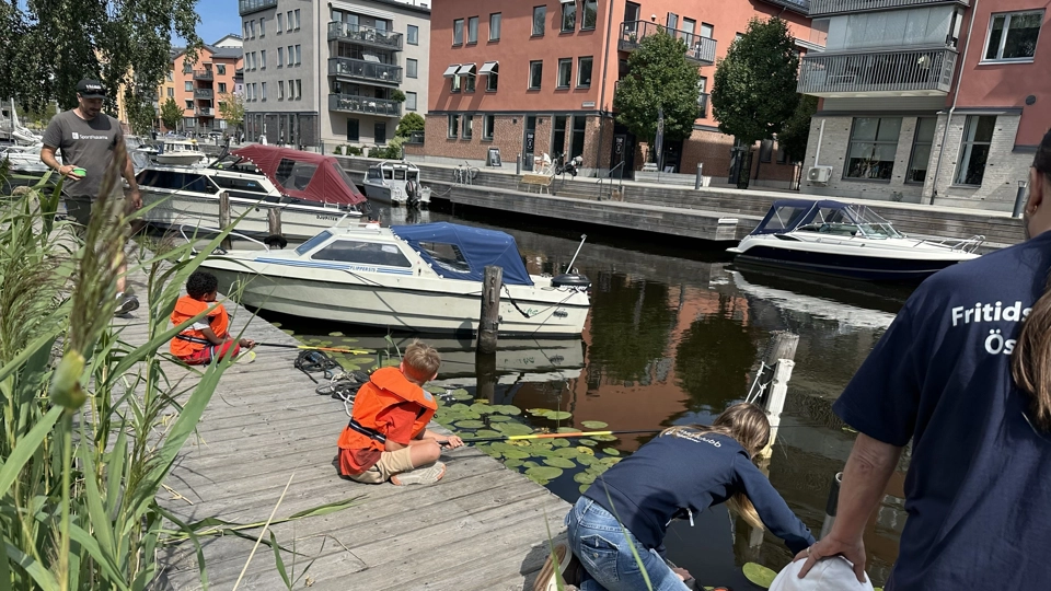 Barn sitter på en brygga vid Åkerskanal och metar