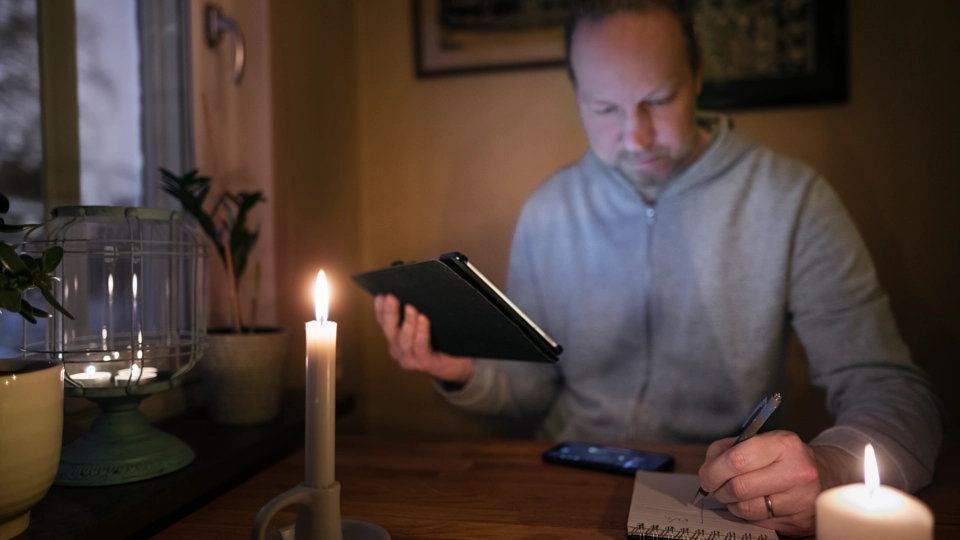 En person sitter i mörkret med tända ljus.