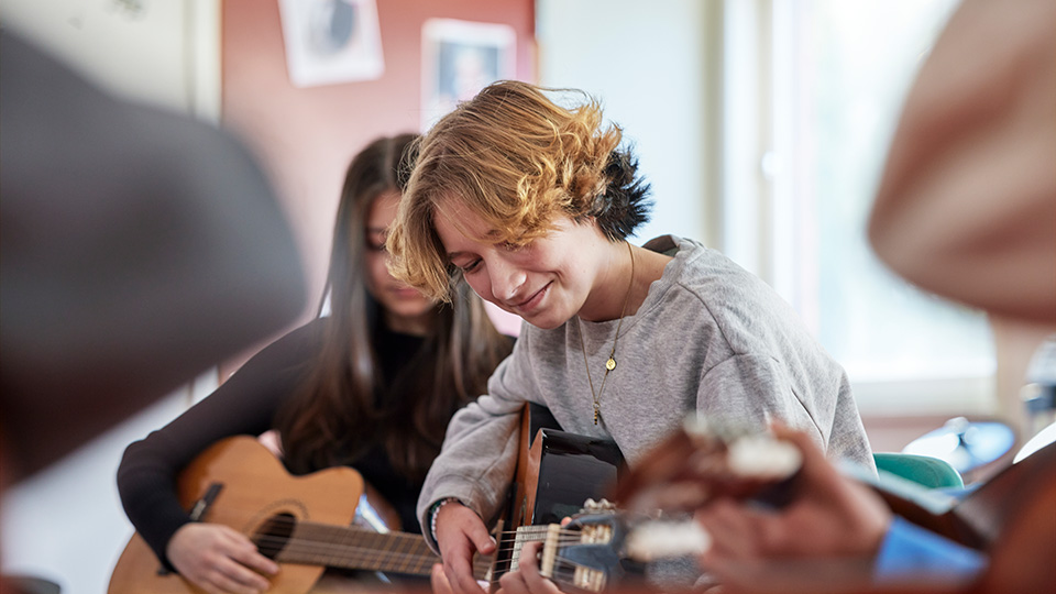 Två unga personer spelar gitarr.