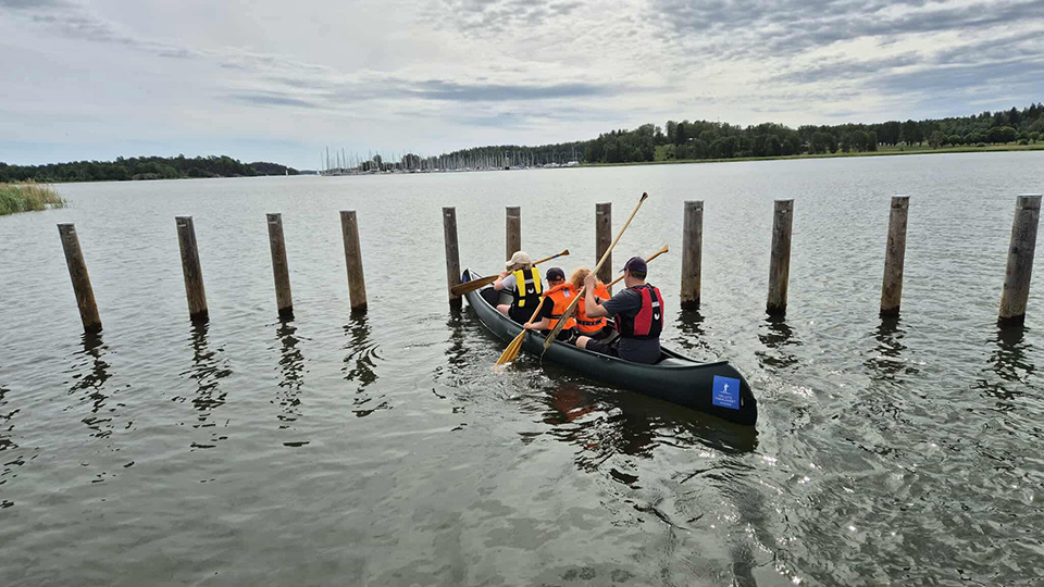 Fyra personer i varierande åldrar paddlar kanot.