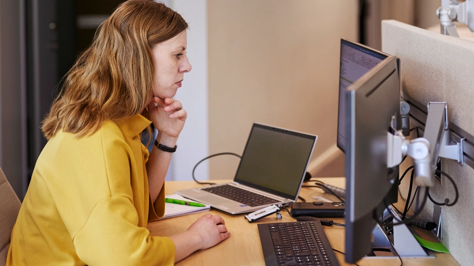Kvinna sitter framför datorskärmar