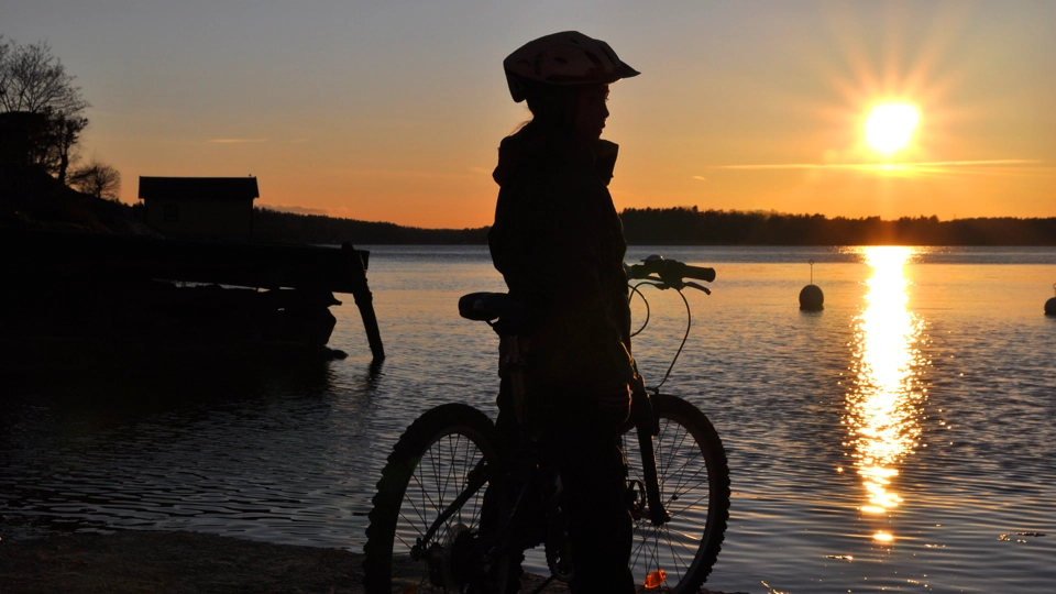 En person som står bredvid en cykel i närheten av ett vattendrag.