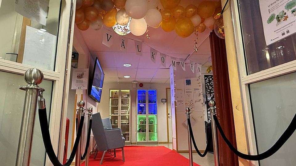 Festligt dekorerad entré med guldballonger och röd matta samt texten Välkommen i taket.