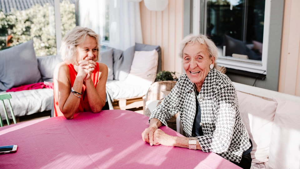 Två glada damer sitter vid ett bord.