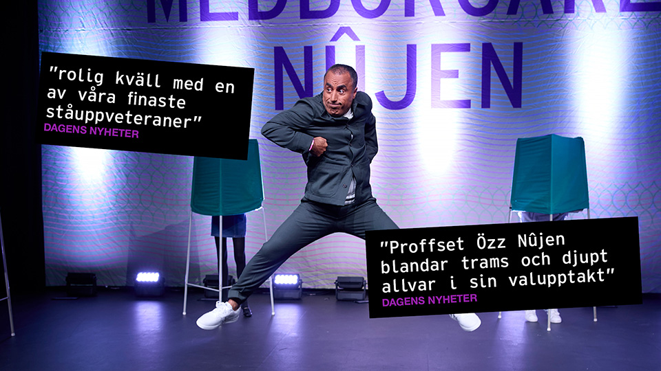 En man i tajt kostym står i en extremt bredbent ställning.