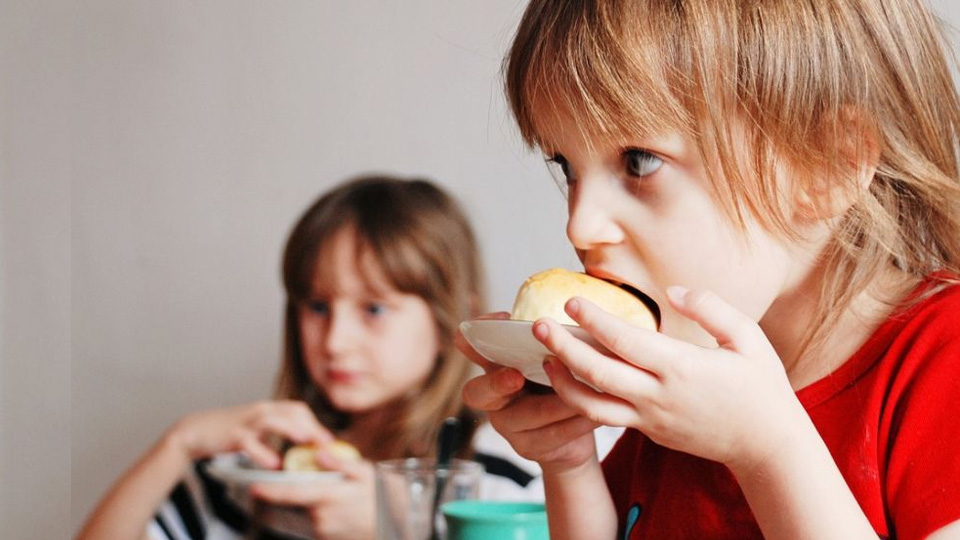 Två barn tuggar i sig smörgås.