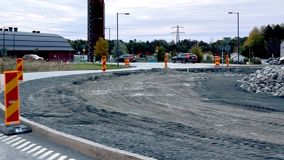 En cirkulationsplats fylld av grushögar omgärdad av gulröda trafikkoner.
