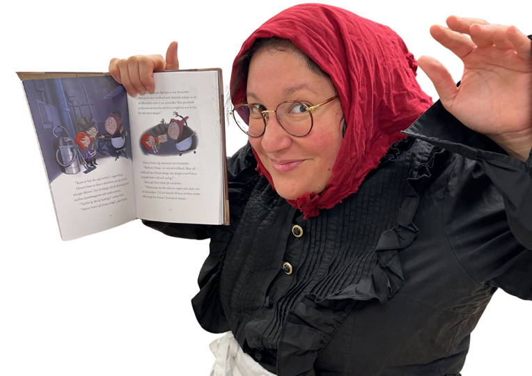 En kvinna klädd i huckle håller upp en bok.