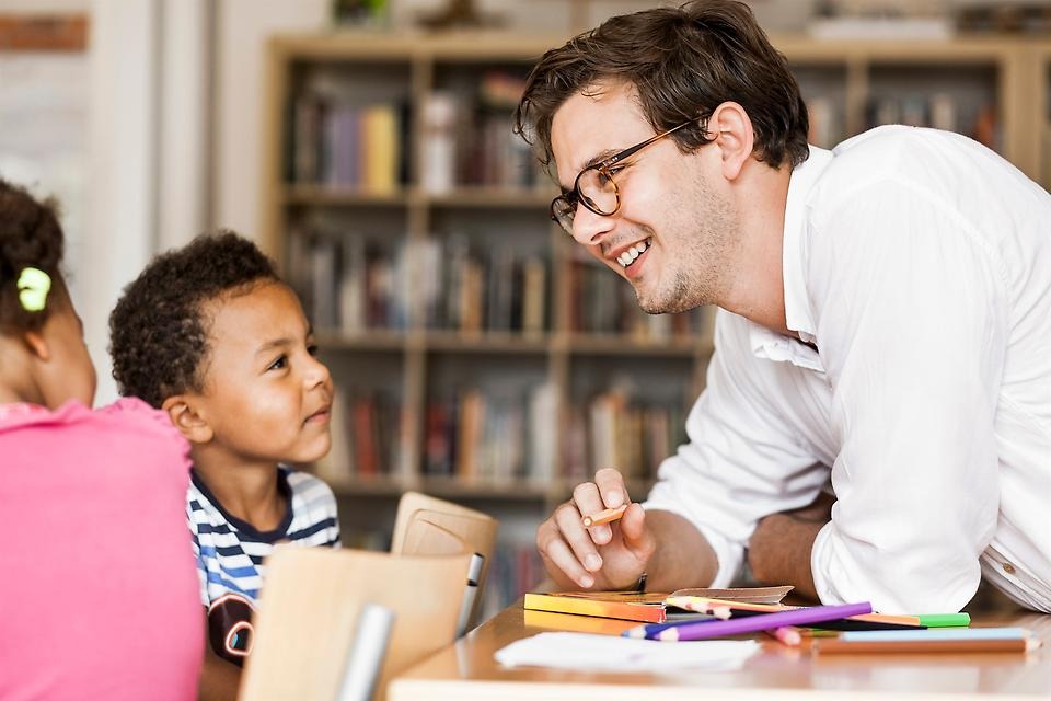 En lärare och en elev pratar i ett klassrum.