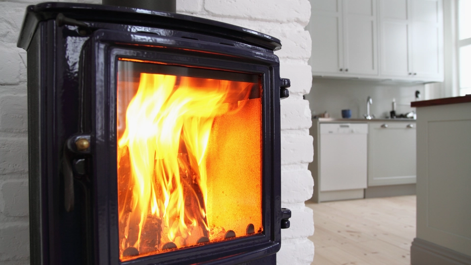 En svart braskamin där det brinner en fin eld