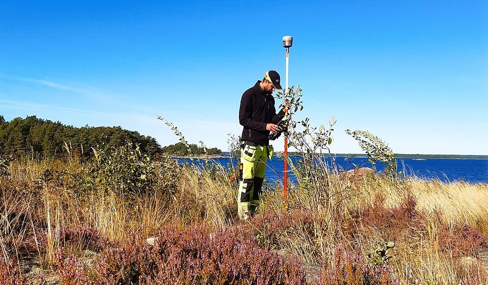 Mätningsingenjör står med mätinstrument i skärgården 
