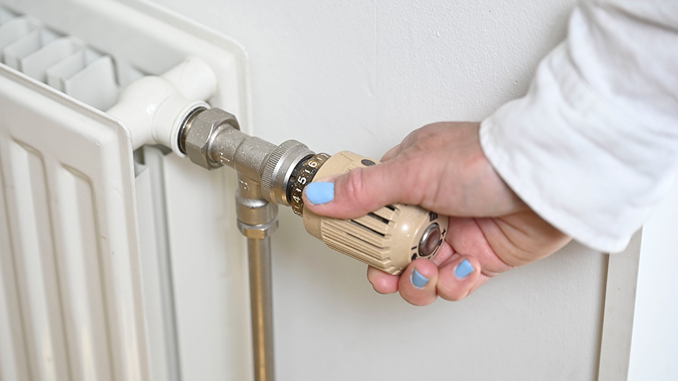 En hand håller i vredet på ett element.