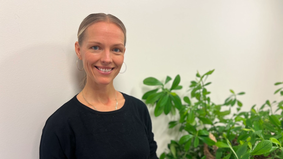 En kvinna står framför en krukväxt.