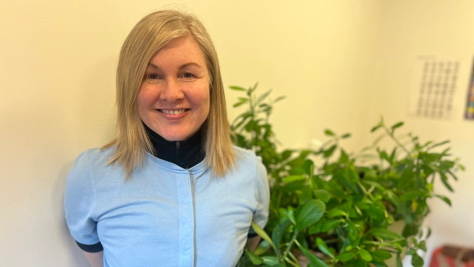 En kvinna som står bredvid en krukväxt.