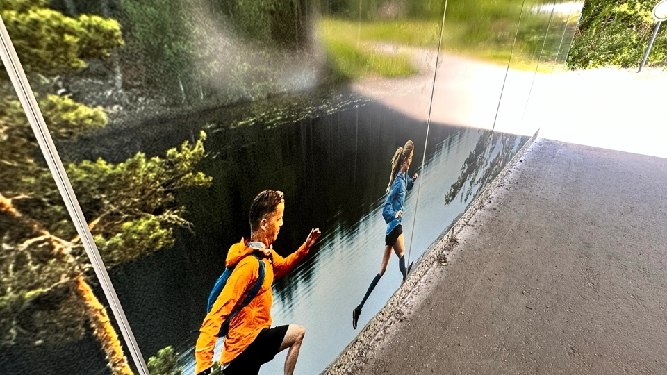 Motiv med frilulftsklädda personer som springer i Trastsjöskogen sitter på väggarna i en gångtunnel som leder mot Trastsjöskogen.