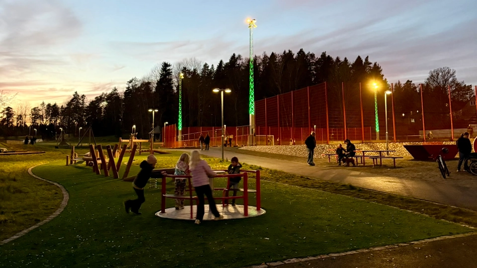 Barn leker på en lekplats i Skånstaparken. Det är kväll och mörkt, men belysningen är god.