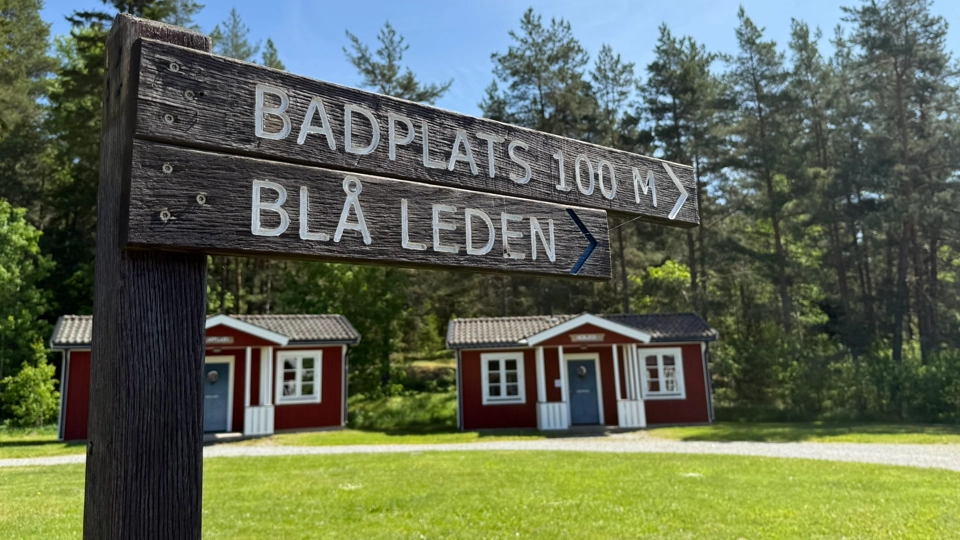 En träskylt framför en röda stugor.