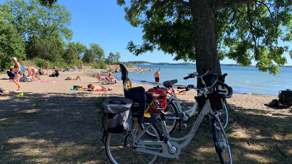 En sandstrand vid havet med många människor och en cykel i förgrunden.