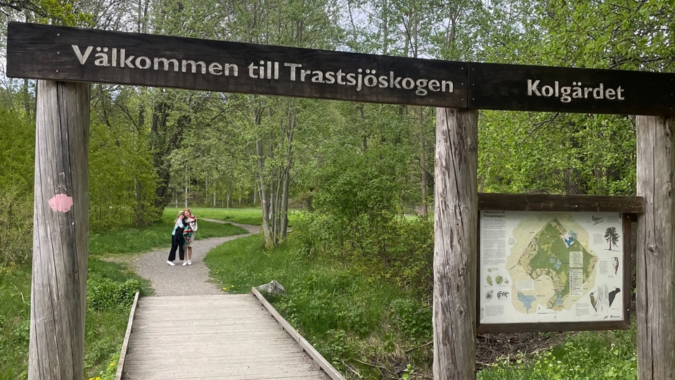En portal till en naturstig. Överst står "Välkommen till Trastsjöskogen".