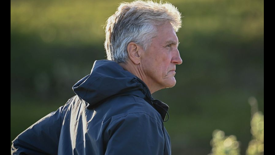 En gråhårig man i profil. Han är klädd i vindskyddsjacka och står utomhus.