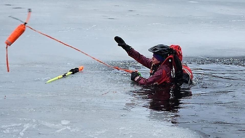 En person är nere i en isvak och håller upp ena armen vid isvakens kant