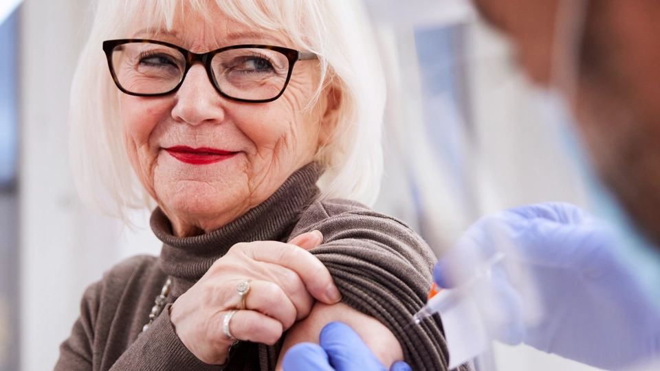 En äldre kvinna får en vaccination av sjukvårdspersonal