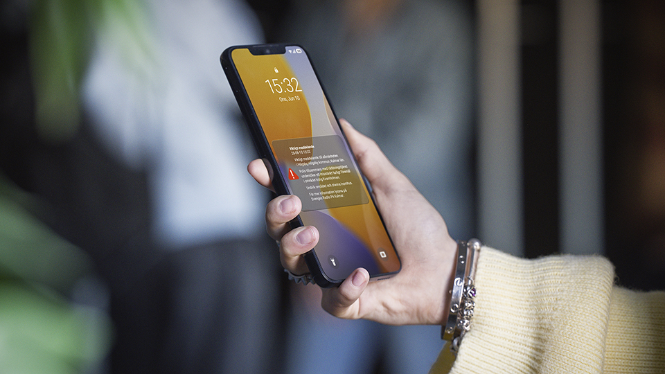 Närbild på en hand som håller i en mobiltelefon med ett varningsmeddelande