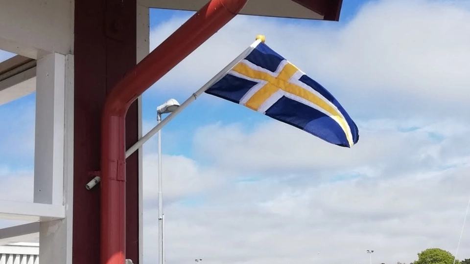 En flagga på sidan av en byggnad intill ett vattenområde.
