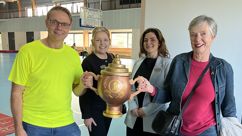 4 personer ler och håller i en pokal.