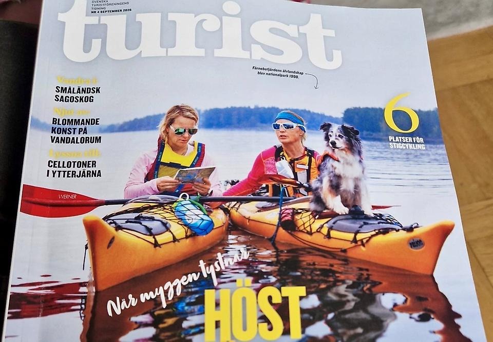 Omslagsbild från tidning med två personer i kanot i vattendrag där en hund står på en av kanoterna